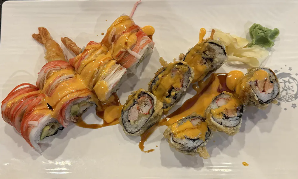 Tempura sushi roll platter topped with crab strips, spicy orange sauce, ginger and wasabi on glossy white plate at Sakura Japanese Restaurant, a Japanese restaurant in Wilmington