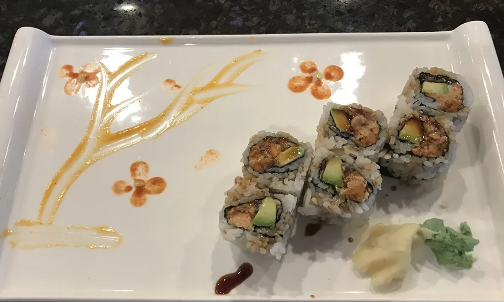 Small salmon avocado maki rolls plated with artistic brown sauce floral designs alongside ginger and wasabi at Sakura Japanese Restaurant, a Japanese restaurant in Wilmington